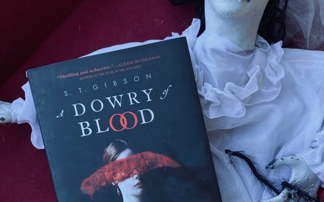 A Dowry of Blood by S.T. Gibson book pictured on top of a creepy white Halloween doll