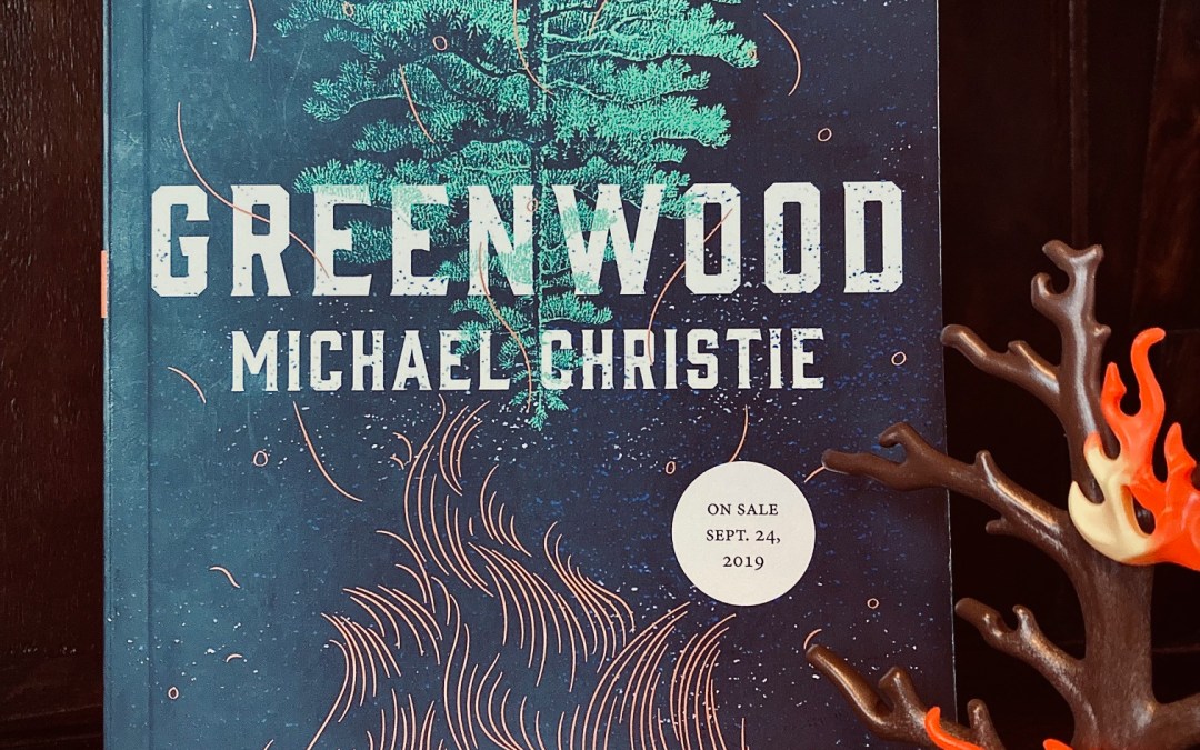 picture of Greenwood by Michael Christie book, next to a small plastic tree with flames on it