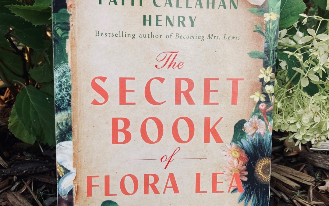 The Secret Book of Flora Lea by Patti Callahan Henry book pictured underneath a flowering bush