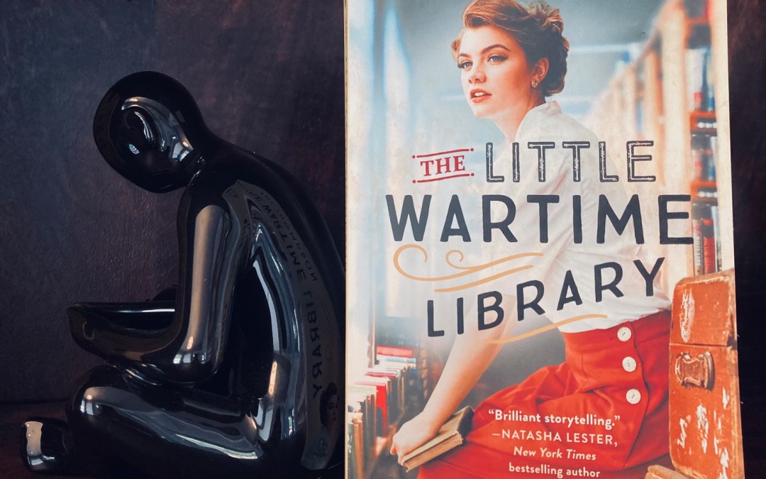 The Little Wartime Library by Kate Thompson book pictured beside a black figurine bent over a book