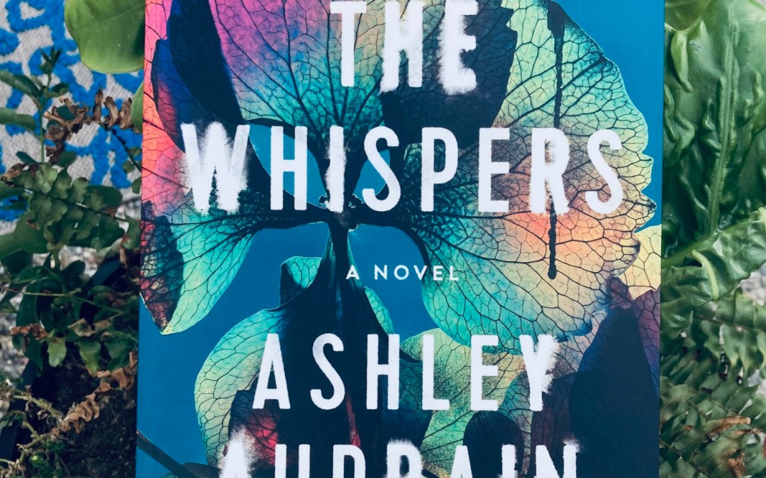 The Whispers by Ashley Audrain book pictured on green leaves
