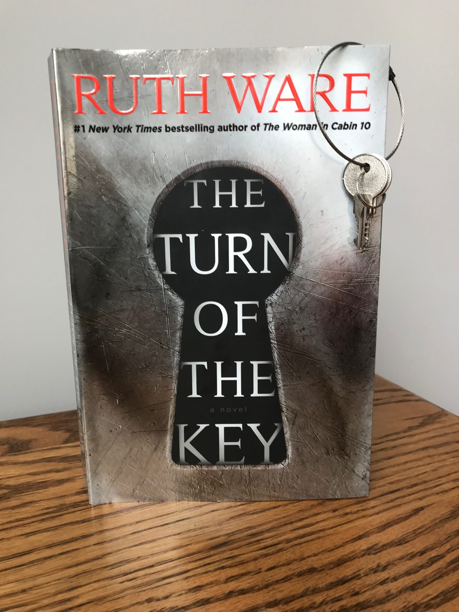 picture of The Turn of the Key book by Ruth Ware, with a circular metal clasp holding two keys hanging off the top of the book