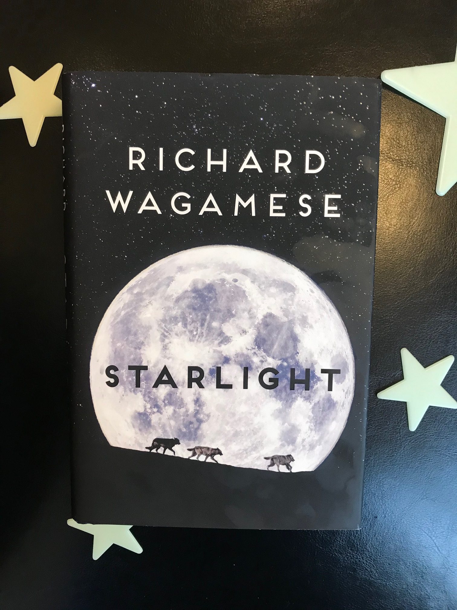 Starlight by Richard Wagamese book pictured on a black background with white plastic glow-in-the-dark stars surrounding it