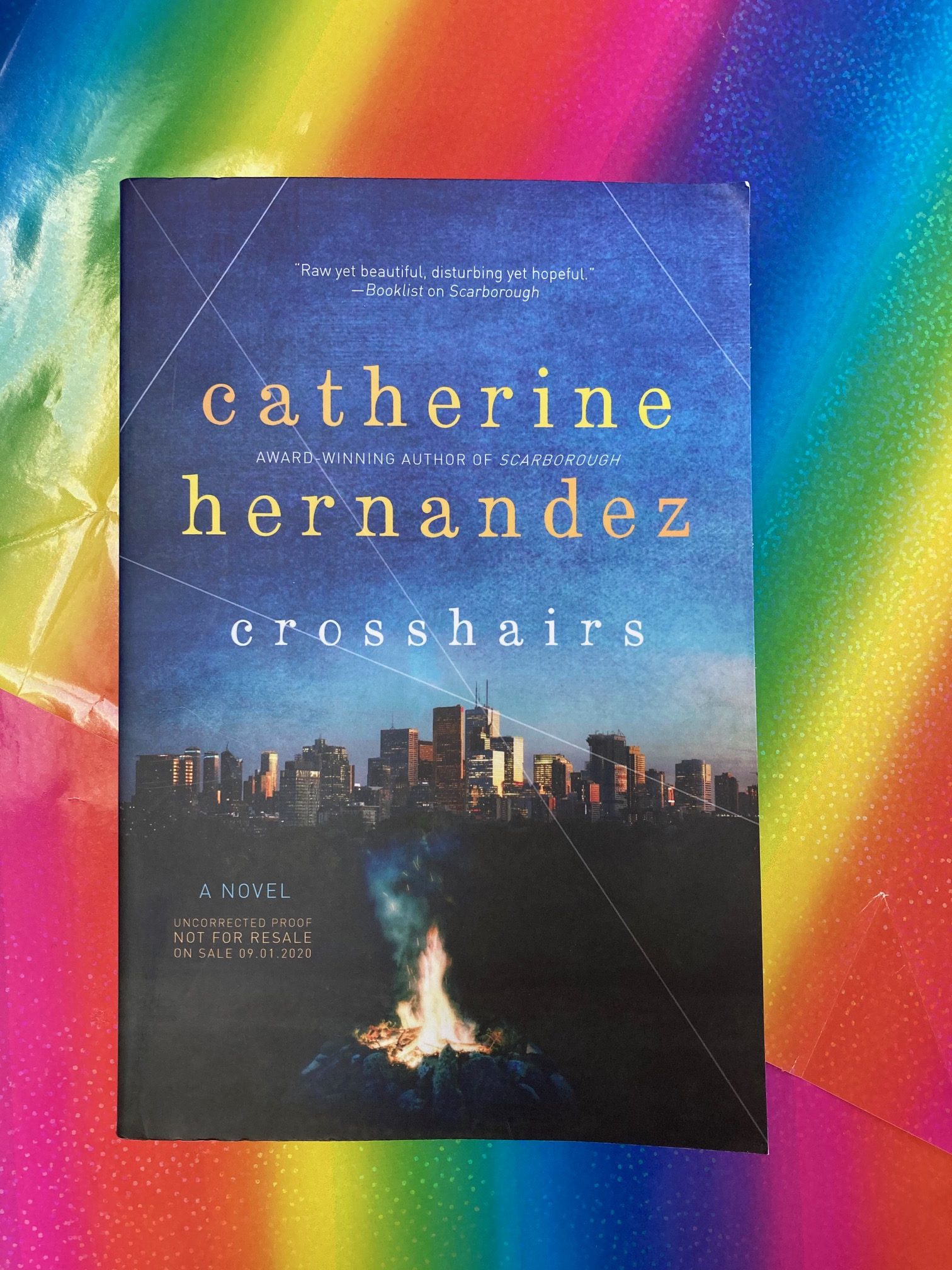 Crosshairs by Catherine Hernandez book on a sheet of rainbow paper