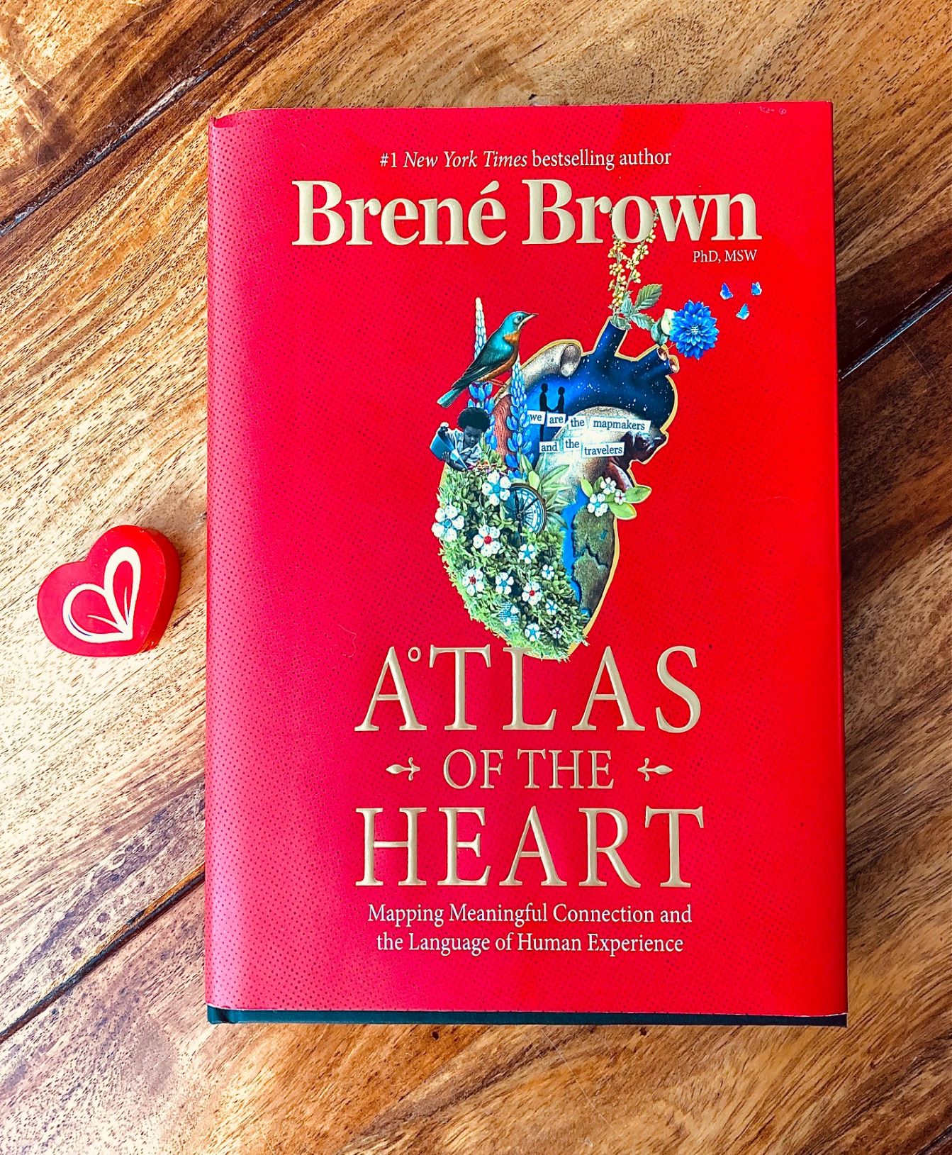 Atlas of the Heart by Brene Brown book pictured next to a red wooden heart