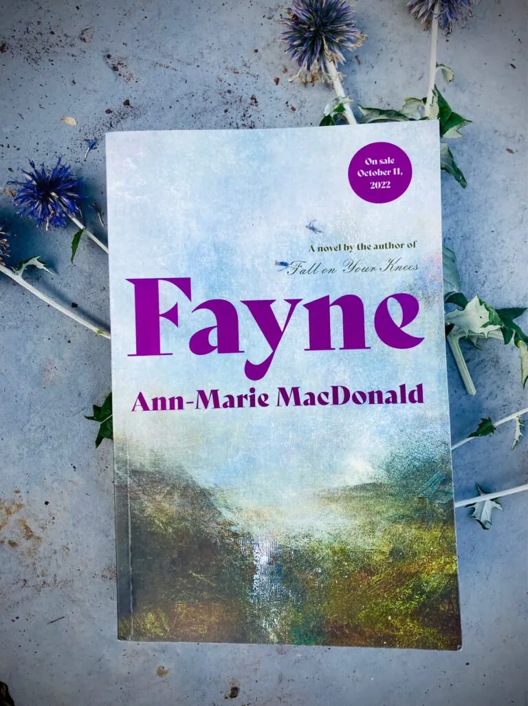 the book Fayne by Ann-Marie MacDonald on top of a few cut floors lying on a concrete floor