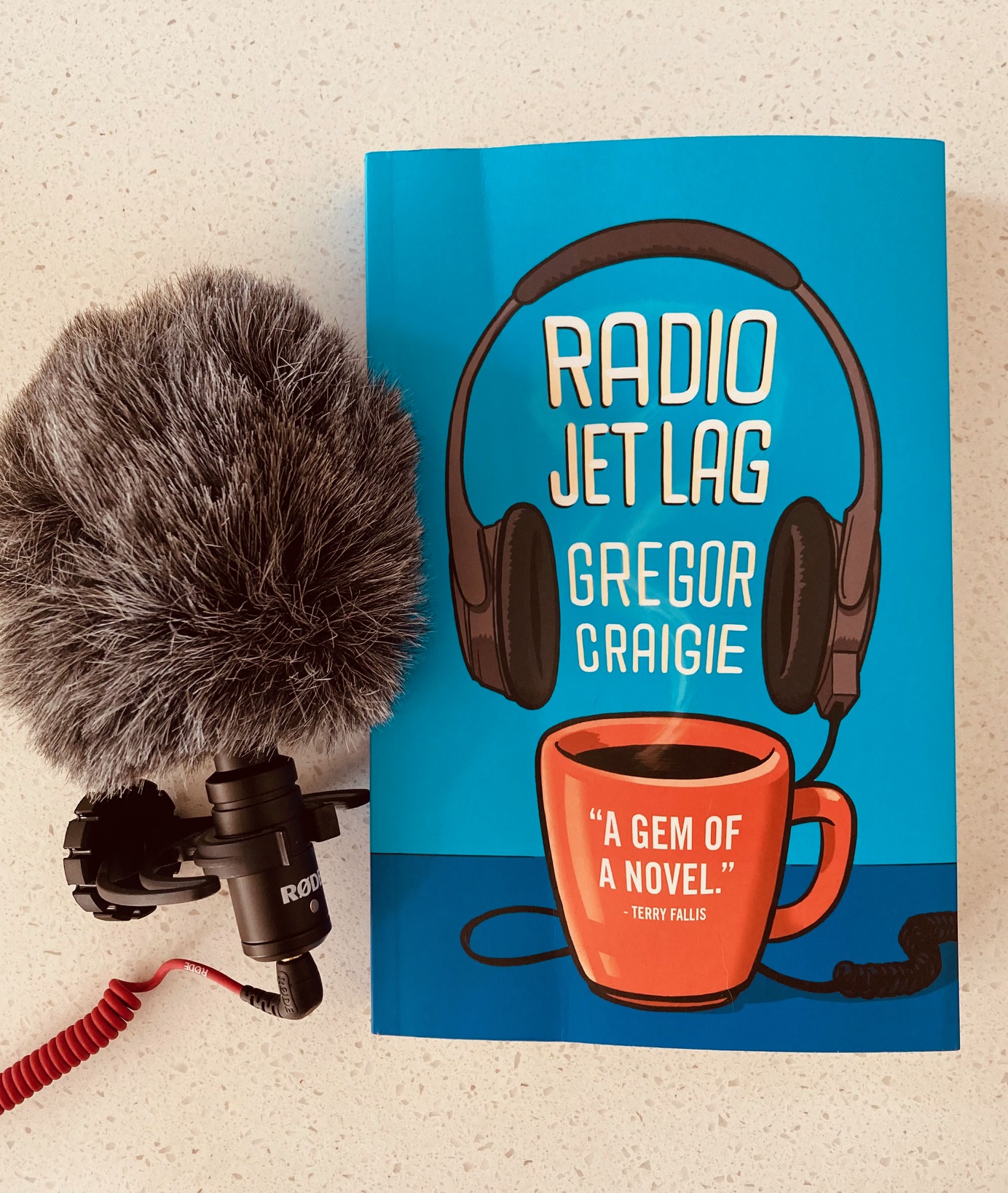 Radio Jet Lag by Gregor Craigie book next to a fuzzy black microphone on a white background