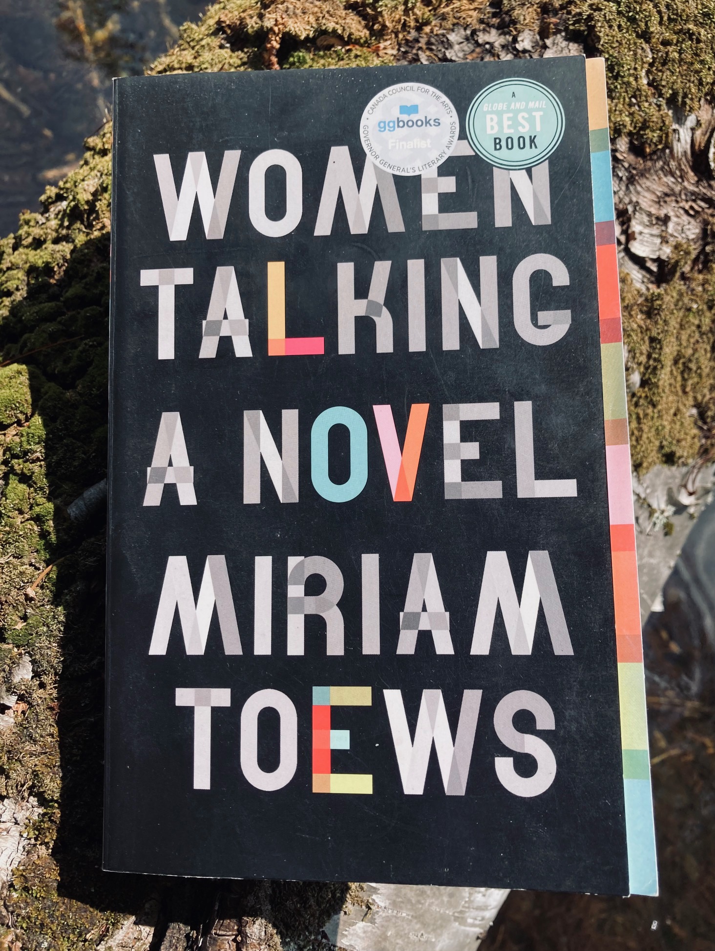 Women Talking by Miriam Toews book pictured on a moss covered branch