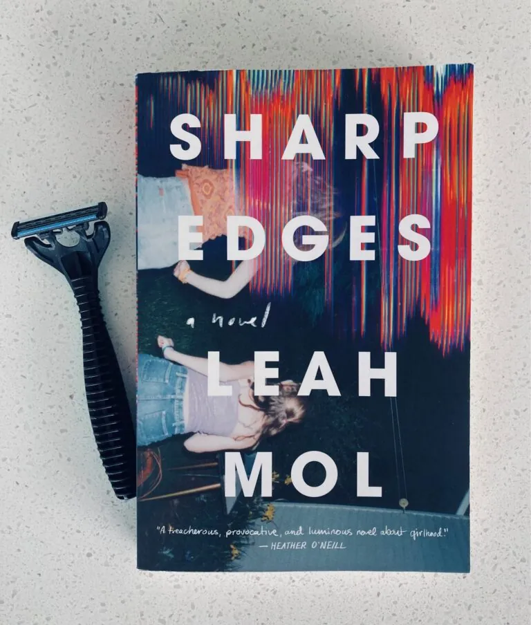 Sharp Edges by Leah Mol book pictured beside a black razor blade