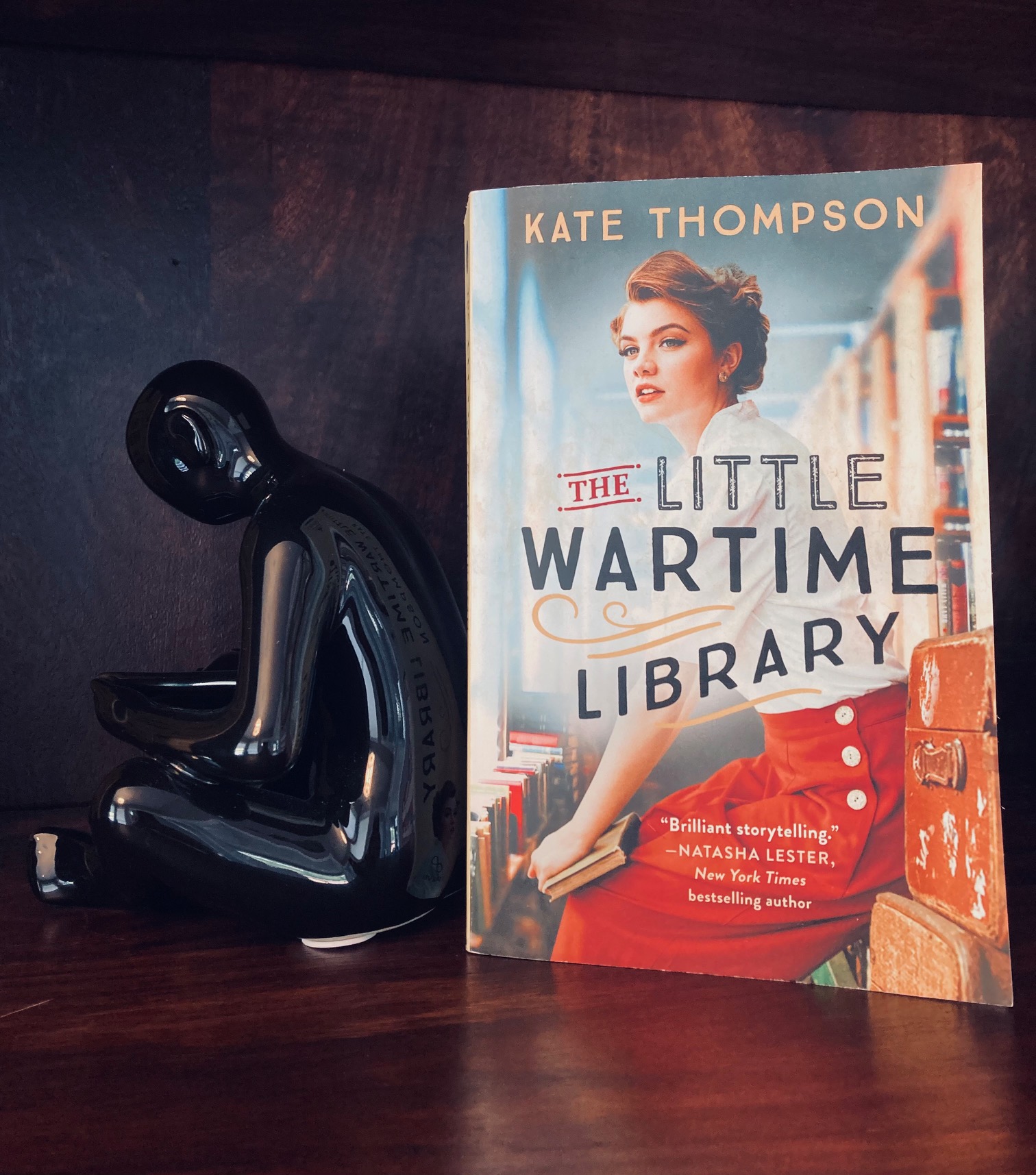 The Little Wartime Library by Kate Thompson book pictured beside a black figurine bent over a book