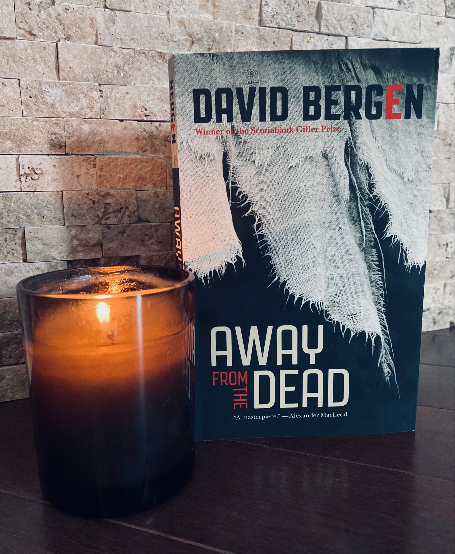 Away from the Dead by David Bergen book pictured beside a candle burning