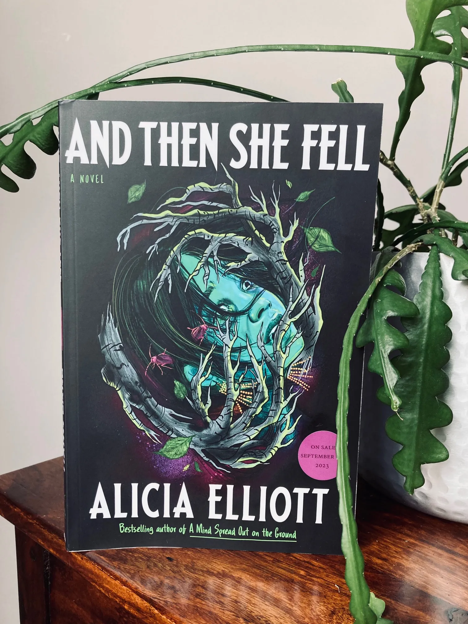And Then She Fell by Alicia Elliott book surrounded by creeping plants