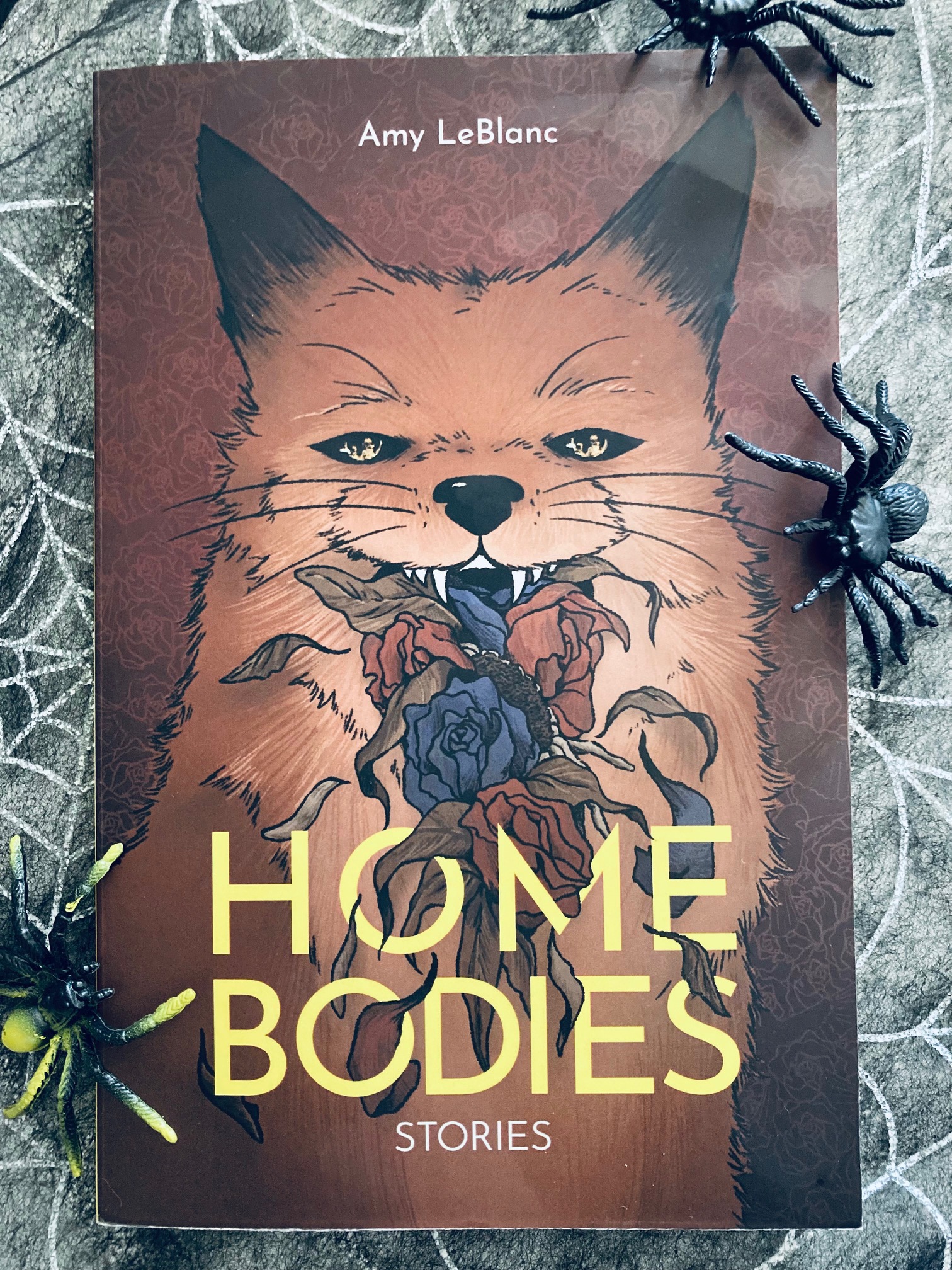 Home Bodies by Amy LeBlanc book pictured with plastic spiders on it