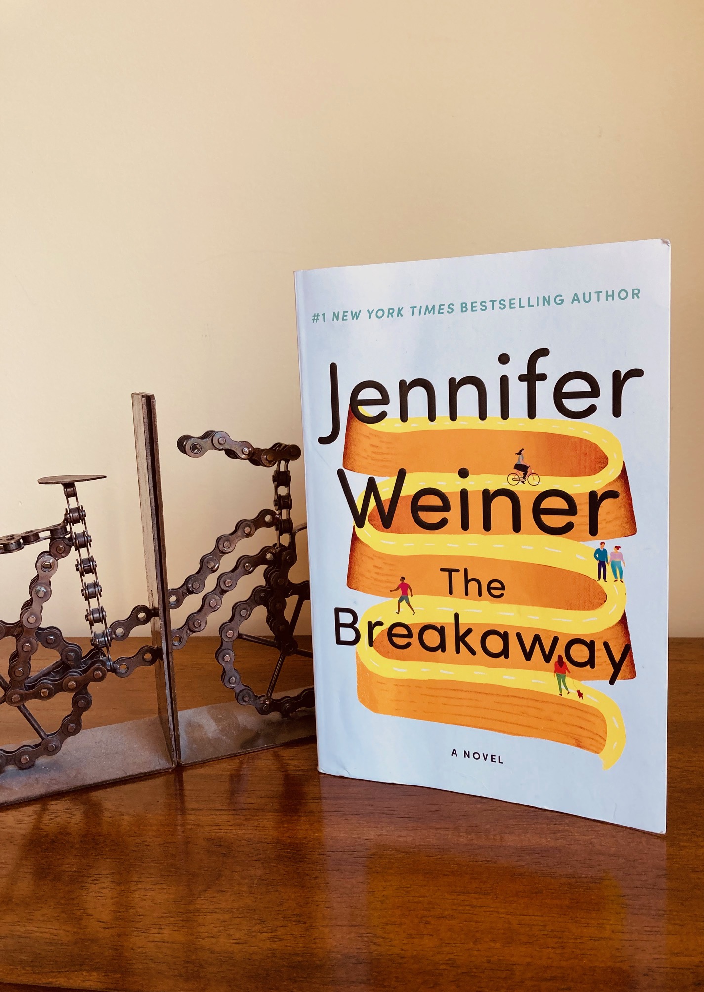 The Breakaway by Jennifer Weiner book pictured beside a metal bike bookend